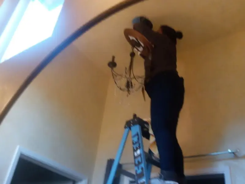 Electrician installing a chandelier in a Alva residence